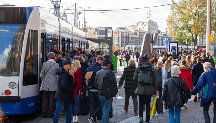 Een afbeelding van een groep mensen van alle leeftijdsgroepen bij een tram, Amsterdam, Nederland