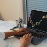 Een afbeelding van een handelaar die naar een grafiek van een crypto munt of aandeel kijkt