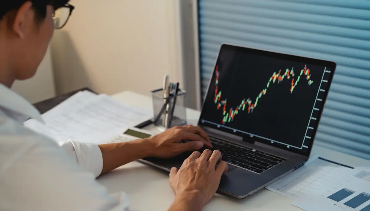 Een afbeelding van een handelaar die naar een grafiek van een crypto munt of aandeel kijkt