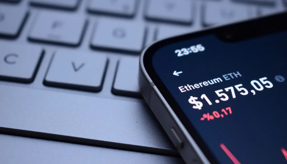 Een afbeelding van een lage, rode ethereum (ETH) koers op een mobiele telefoon bij een toetsenbord