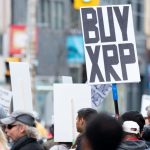 Een afbeelding van een protest waarbij iemand een bord met 'koop XRP', ookwel Ripple genoemd, ophoudt