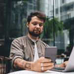 Man kijkt naar mobiel achter latop