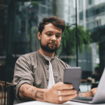 Man kijkt naar mobiel achter latop