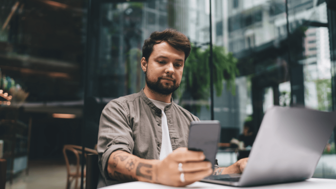 Man kijkt naar mobiel achter latop