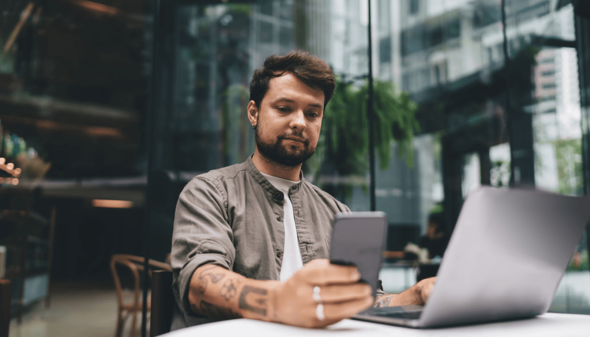 Man kijkt naar mobiel achter latop