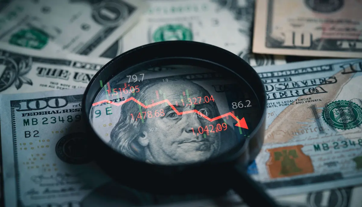 Een afbeelding van een Amerikaanse dollar en een vergrootglas met daarin een dalende rode koers met cijfers