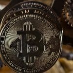 Een afbeelding van een bitcoin (BTC) munt bij een aantal gouden tandwielen