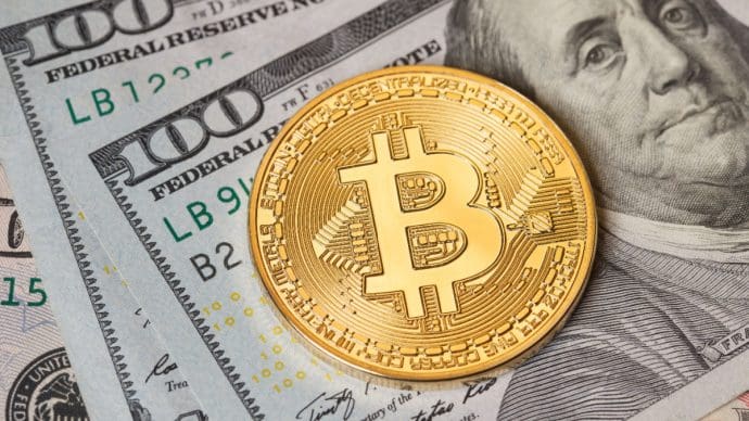 Een afbeelding van een bitcoin (BTC) munt op Amerikaans briefgeld