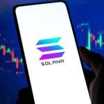 Een afbeelding van een mobiele telefoon met het Solana (SOL) logo op de voorkant en op de achtergrond een stijgende grafiek van een koers van een crypto