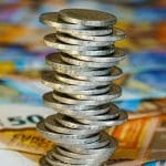 Een afbeelding van een toren van twee euromunten uit de EU, met daaronder briefgeld van 50 euro