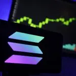 Een afbeelding van het Solana (SOL) logo met op de achtergrond een stijgende crypto koers te zien als grafiek op een beeldscherm