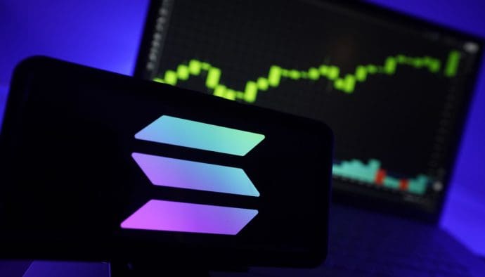 Een afbeelding van het Solana (SOL) logo met op de achtergrond een stijgende crypto koers te zien als grafiek op een beeldscherm