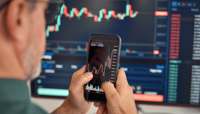 afbeelding van cryptotrader met mobiel en koersgrafiek
