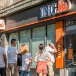 Een afbeelding van een ING bank in een grote stad met een rij klanten erbij