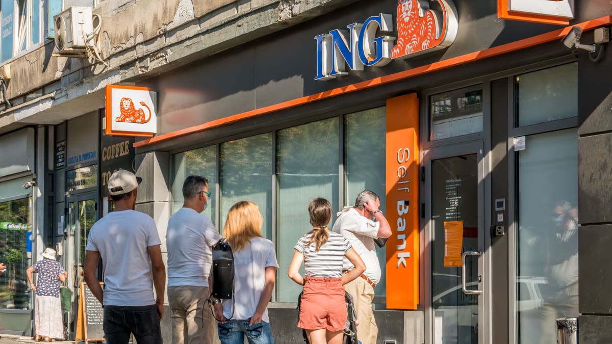 Een afbeelding van een ING bank in een grote stad met een rij klanten erbij