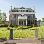 Een afbeelding van een Nederlandse villa met een grote tuin