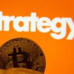 Een afbeelding van een aantal bitcoin munten met op de achtergrond het logo van Strategy, het bedrijf met de meeste bitcoin Een afbeelding van een aantal bitcoin munten met op de achtergrond het logo van Strategy, het bedrijf met de meeste bitcoin