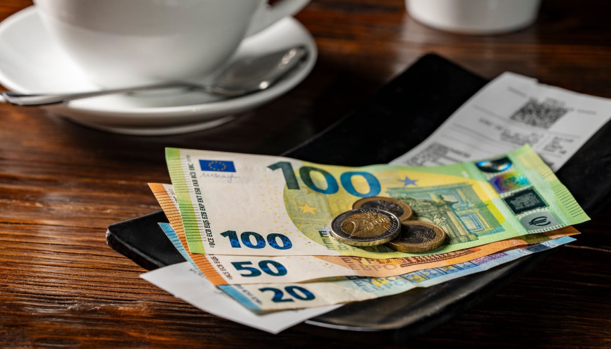 Een afbeelding van een bakje met fooi, waar enkele biljetten van 100, 50 en 20 euro liggen met wat euromunten