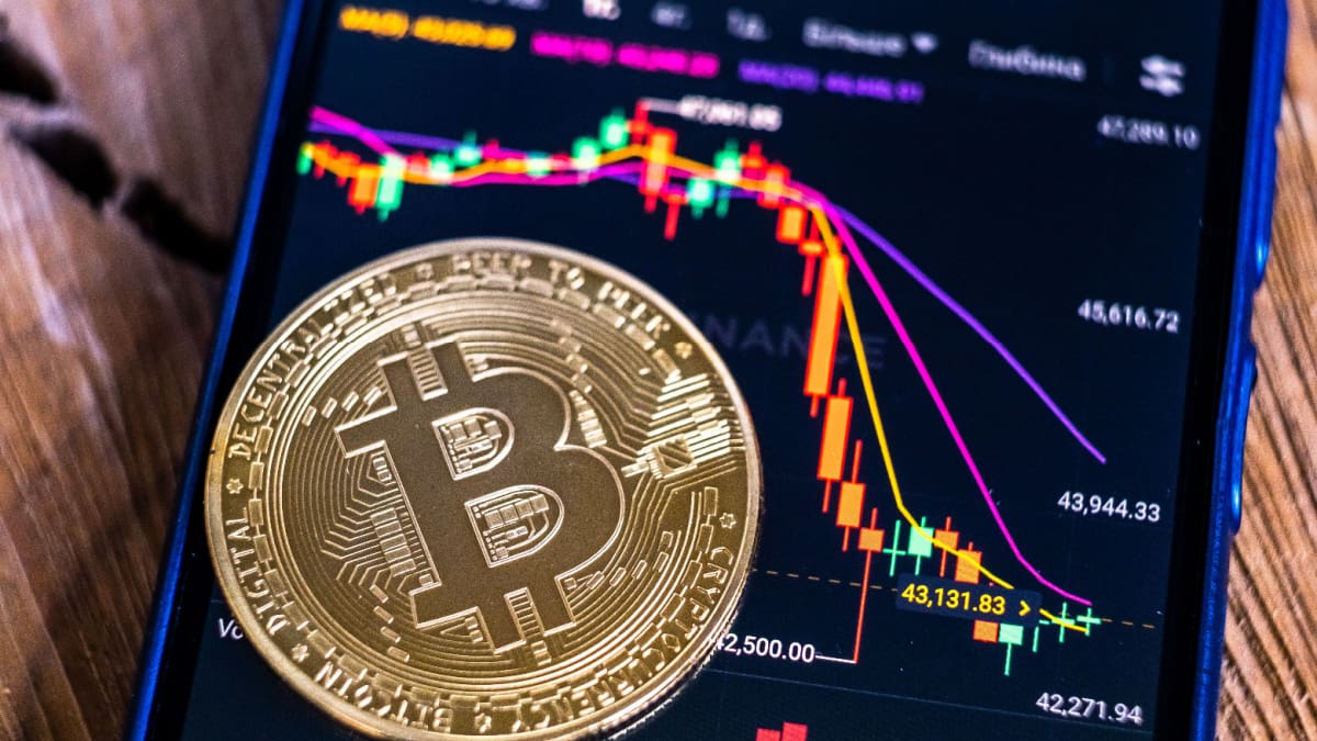 Een afbeelding van een bitcoin munt op een cryptobeurs met daarbij een bijbehorende grafiek en koers die hard crasht