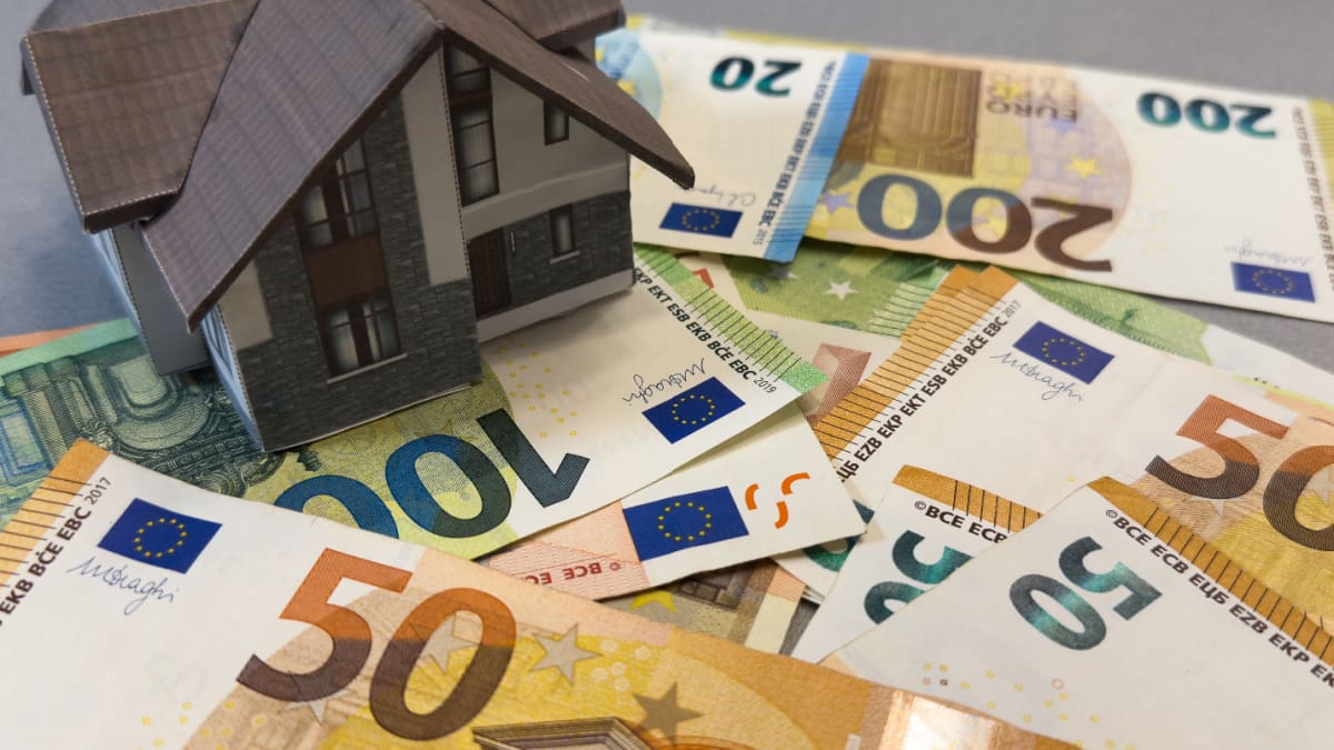 Een afbeelding van een huis op een stapel euro bankbiljetten