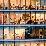 Een afbeelding van een kantoor met vele kantoormedewerkers in een groot gebouw van meerdere verdiepingen