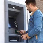 Een afbeelding van een man die aan het pinnen is bij een geldautomaat van een onbekende bank of bedrijf