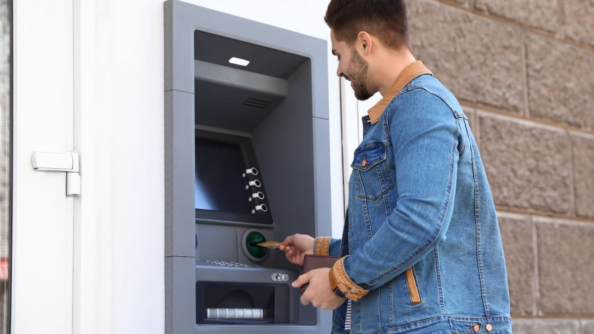 Een afbeelding van een man die aan het pinnen is bij een geldautomaat van een onbekende bank of bedrijf