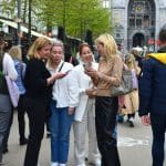 Een afbeelding van een paar vrouwen die hun mobiel bekijken op een drukke plek in Antwerpen Een afbeelding van een paar vrouwen die hun mobiel bekijken op een drukke plek in Antwerpen