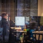 Een afbeelding van een werknemer die werkt op een druk kantoor, gefotografeerd van buitenaf Werknemers steeds duurder: zo hoog liggen de kosten nu per uur