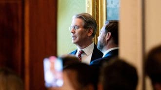 De Amerikaanse president van Financiën, Scott Bessent, te zien in het Witte Huis door een kier in gesprek met JD Vance