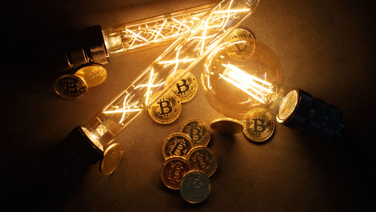 Een afbeelding van bitcoin (BTC) munten tussen een aantal brandende lampen