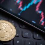 Een afbeelding van de XRP koers op de achtergrond met op de voorgrond een XRP munt, de crypto van Ripple