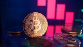 Een afbeelding van een bitcoin (BTC) munt met een dalende rode koers op de achtergrond