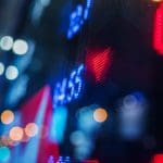 Een afbeelding van een bord met aandelen met daarop rode cijfers