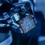 Een afbeelding van een computerchip, mogelijk die van een quantum computer, die wordt vastgehouden door een robotarm