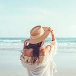 Een afbeelding van een vrouw bij een strand in de zomer die aan het genieten is van haar vakantie