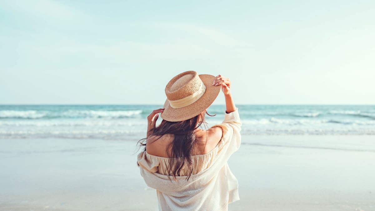 Een afbeelding van een vrouw bij een strand in de zomer die aan het genieten is van haar vakantie