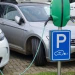 Een afbeelding van elektrische auto's in Nederland die worden opgeladen bij een laadpaal op een parkeerplaats