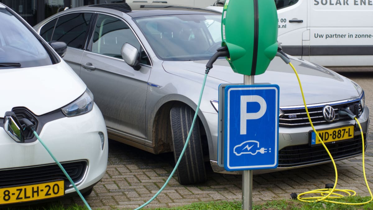 Een afbeelding van elektrische auto's in Nederland die worden opgeladen bij een laadpaal op een parkeerplaats