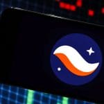 Een afbeelding van het logo van cryptomunt starknet op een mobiele telefoon met op de achtergrond marktdata en grafieken