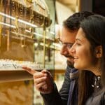 Een stel kijkt naar gouden sieraden die zijn belegd met edelstenen bij een juwelier