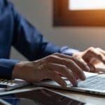 man typt iets op laptop