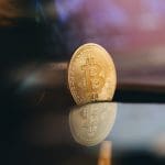 Een afbeelding van een bitcoin (BTC) munt bij een laptop met een grafiek