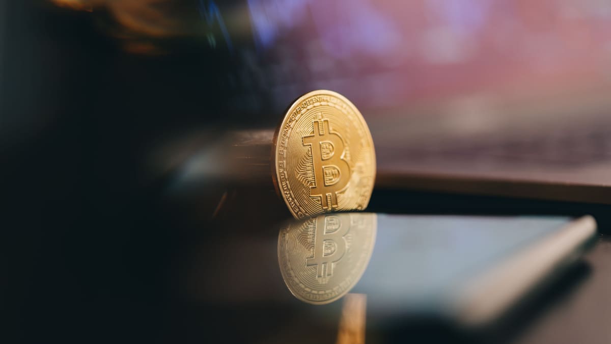 Een afbeelding van een bitcoin (BTC) munt bij een laptop met een grafiek