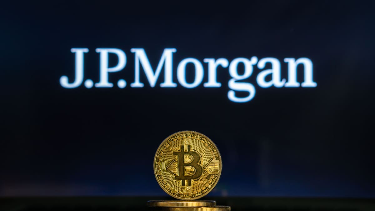Een afbeelding van een bitcoin (BTC) munt met op de achtergrond het logo van JP Morgan, een van de grootste en belangrijkste banken ter wereld