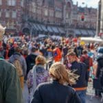 Een afbeelding van een menigte op Koningsdag in Nederland die feest vieren in een straat in Amsterdam