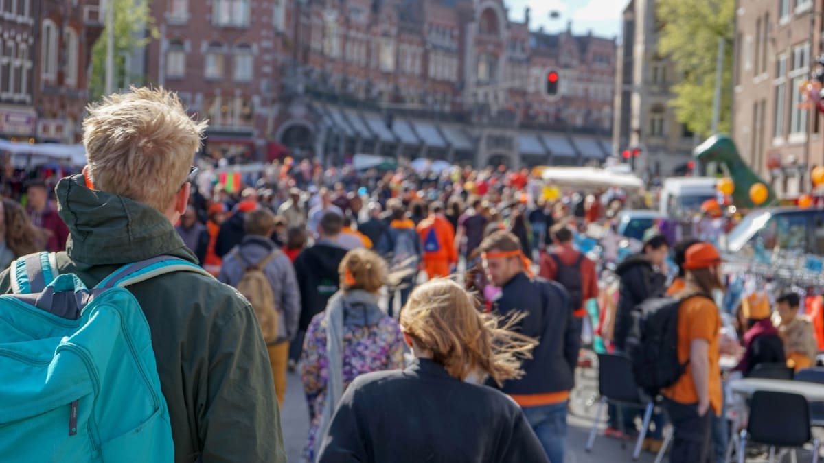 Een afbeelding van een menigte op Koningsdag in Nederland die feest vieren in een straat in Amsterdam