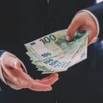 Een afbeelding van een persoon die meerdere honderd euro bankbiljetten vasthoudt
