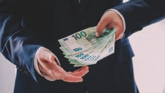 Een afbeelding van een persoon die meerdere honderd euro bankbiljetten vasthoudt