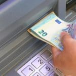 Een afbeelding van iemand die euro bankbiljetten uit een pinautomaat trekt